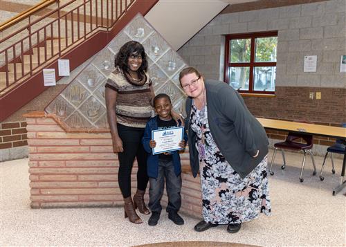 K'veon Mercer, Lincoln's October Stairclimber, poses with his certificate, a family member, and Principal Huffman.
